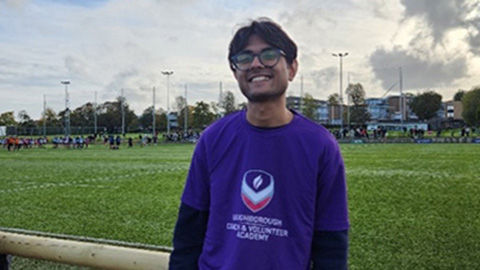 Student standing in front of the rugby pitch